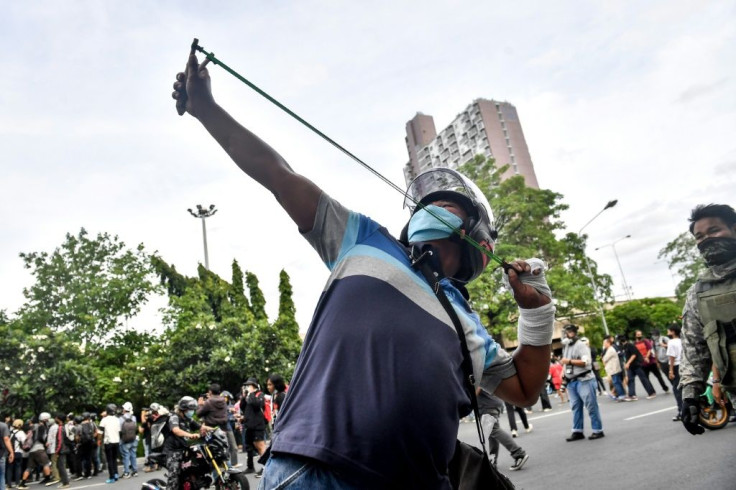 A protester uses a slingshot against police at the rally in Bangkok