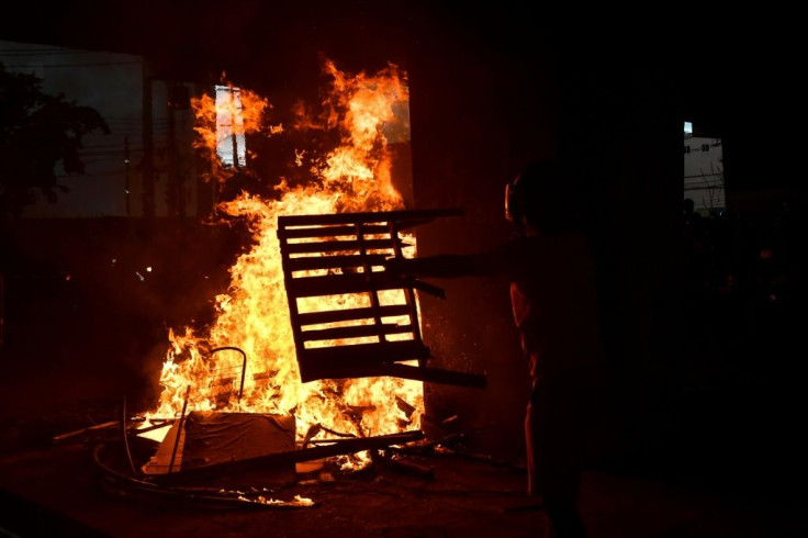 A demonstrator throws a table on a fire during the protest