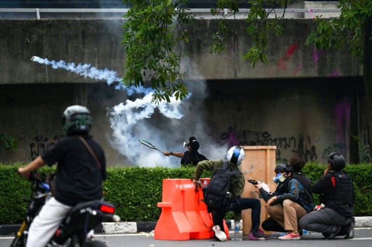 A protester uses a tennis racket to deflect a tear gas canister