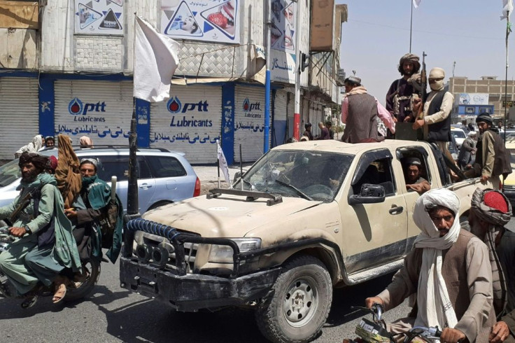 Taliban fighters drive an Afghan National Army (ANA) vehicle through a street in Kandahar