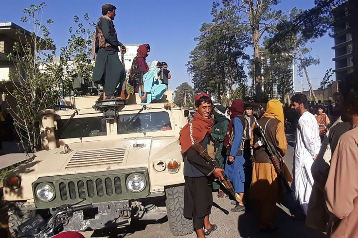 Taliban fighters stand on a vehicle along the roadside in Herat, Afghanistan's third biggest city