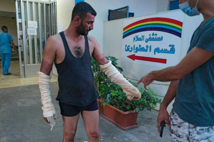 Sterile gauzes on this man's arm treat burns suffered during the fuel tank explosion; he is pictured at the entrance to the Al-Salam Hospital