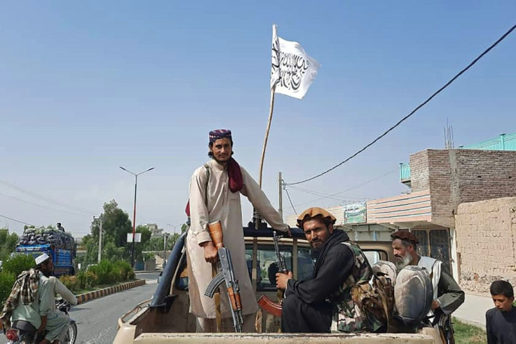 Taliban fighters drive a government vehicle through a conquered city