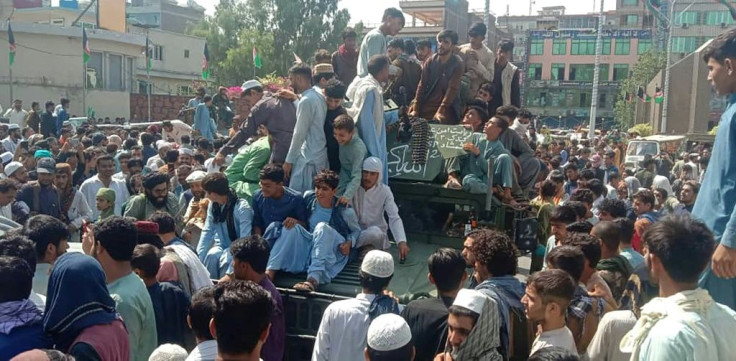 Taliban fighters and local people sit on an Afghan National Army humvee vehicle on a street in Jalalabad