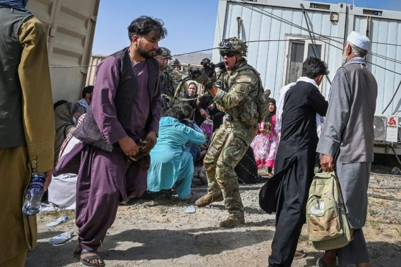 A US soldier (C) points his gun towards an Afghan passenger at the airport in Kabul, where chaotic scenes unfolded after the Taliban took over the country