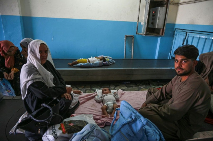 A child rests on an airport luggage conveyor belt as Afghan families wait for a chance to escape Taliban rule