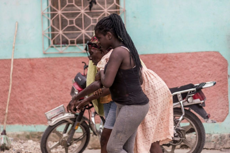 An old woman is helped by a relative near Camp-Perrin, Haiti on August 16, 2021