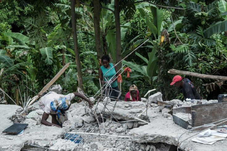 People look search through rubble looking for blankets at their crumbled home near Camp-Perrin, Haiti on August 16, 2021
