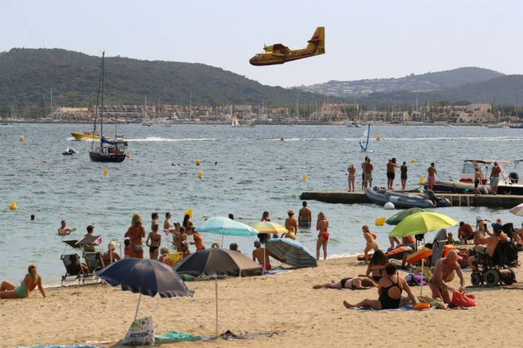 People on the beach watch a Canadair aircraft fill its tank from the sea in the bay of Saint-Tropez.