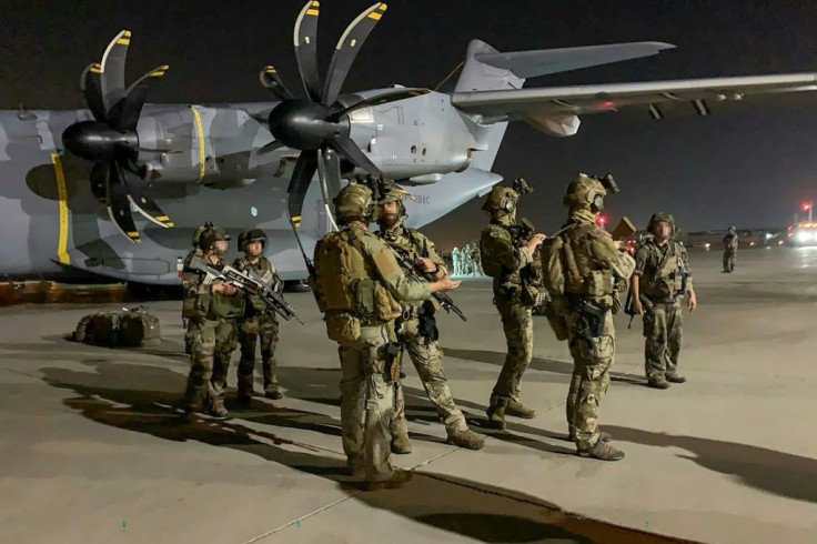 French special forces soldiers stand guard near a military plane at the airport in Kabul after arriving to evacuate French and Afghan nationals following the Taliban's stunning military takeover