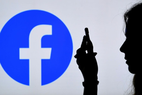 In this photo illustration, a person looks at a smart phone with a Facebook App logo displayed on the background, on August 17, 2021