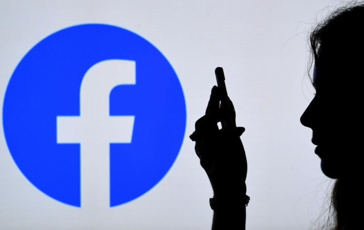 In this photo illustration, a person looks at a smart phone with a Facebook App logo displayed on the background, on August 17, 2021