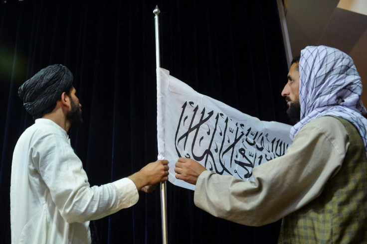 Cadres adjust the Taliban flag ahead of a press conference by its chief spokesman in Kabul