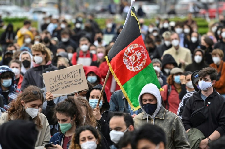 A participant holds up a placard reading 'Evacuate! Air lifts right now!' during a demonstration in Berlin