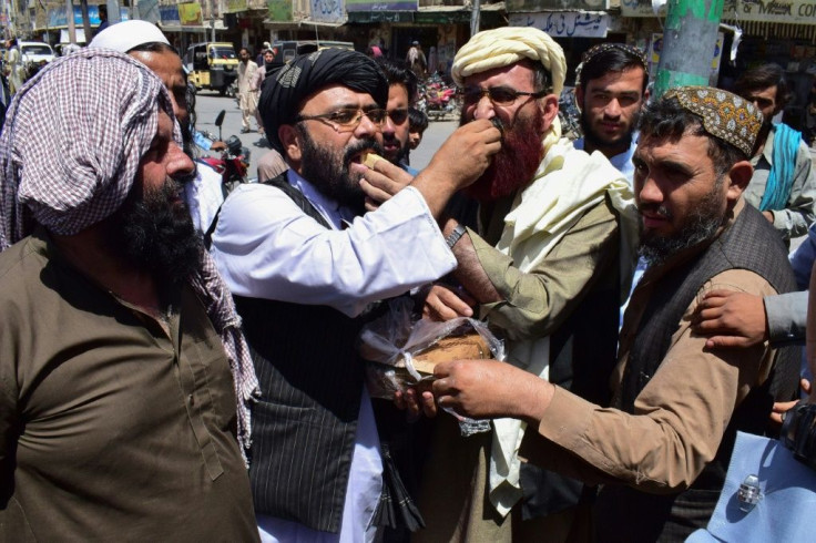 Supporters in Quetta, Pakistan of the hardline pro-Taliban party Jamiat Ulema-i-Islam-Nazaryati eat sweets as they celebrate the capture of cities in Afghanistan by the Taliban on August 13, 2021