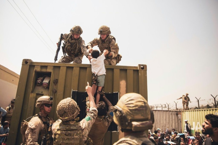 In this image courtesy of the US Central Command Public Affairs, British and Turkish coalition forces, and US Marines assist a child during an evacuation at Hamid Karzai International Airport in Kabul on August 20, 2021