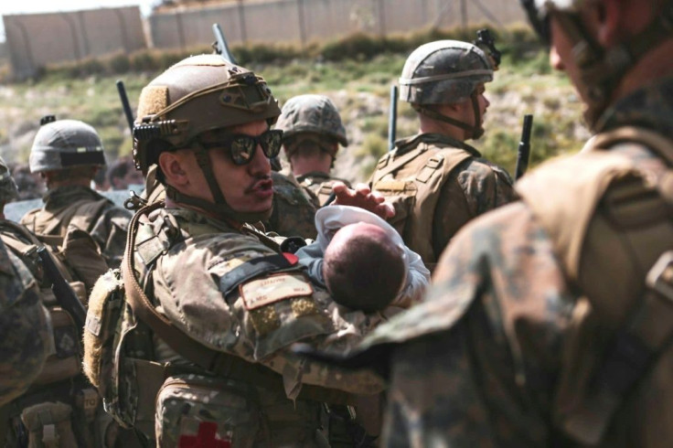 In this image courtesy of the US Central Command Public Affairs, a US airman comforts an infant during an evacuation at Hamid Karzai International Airport