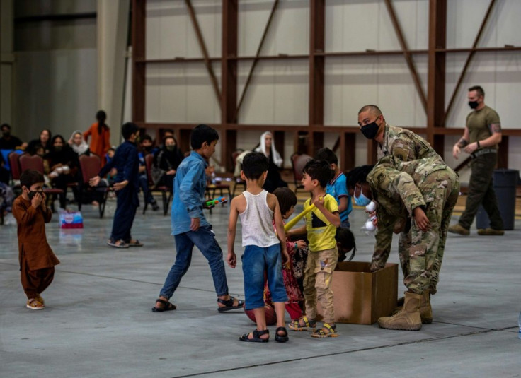 US military personnel are seen handing out sweets to Afghan evacuee children at Al-Udeid air base in Qatar, in an image released by US Central Command