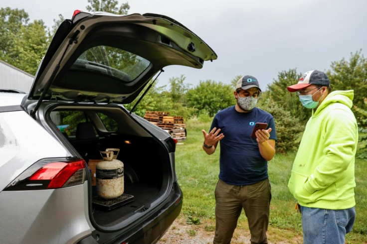 Chad Dorger (L), Senior Environmental Program Associate at Tradewater Refrigerant Solutions, picks up empty refrigerant tanks from Rick Karas (R) in Peotone, Illinois, on August 11, 2021