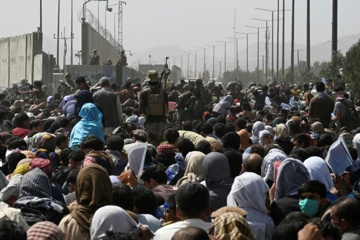 Afghans gather on a roadside near the military part of the airport in Kabul on August 20, 2021, hoping to flee from the country after the Taliban's military takeover