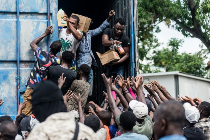 Men hand out supplies to a crowd of earthquake victims during the distribution of food and water in Les Cayes, Haiti, August 20, 2021