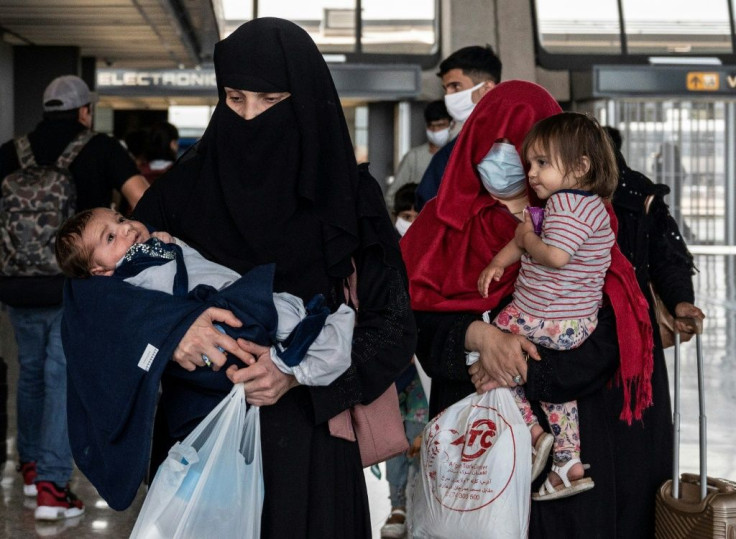 Refugees from Afghanistan are escorted to a waiting bus after arriving at Dulles International Airport in Dulles, Virginia