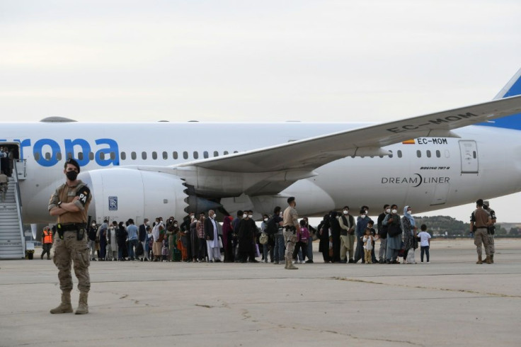 Refugees queue on the tarmac at Torrejon de Ardoz air base near Madrid after disembarking from an evacuation flight from Kabul