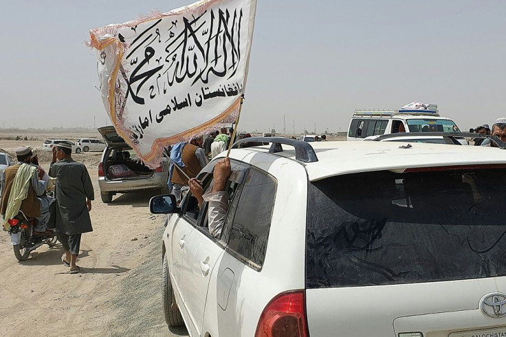 People wave a Taliban flag as they drive through the Pakistani border town of Chaman in July after the Taliban captured the Afghan side of the border