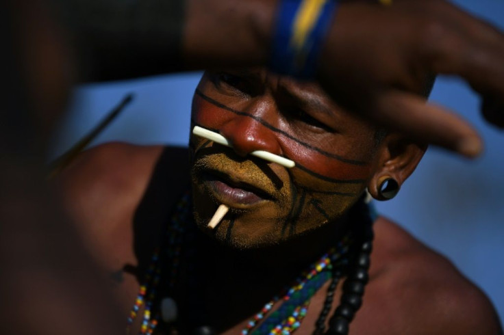 An indigenous man from the Pataxo tribe paints the body of a fellow demonstrator at a protest camp in Brasilia, Brazil on August 25, 2021