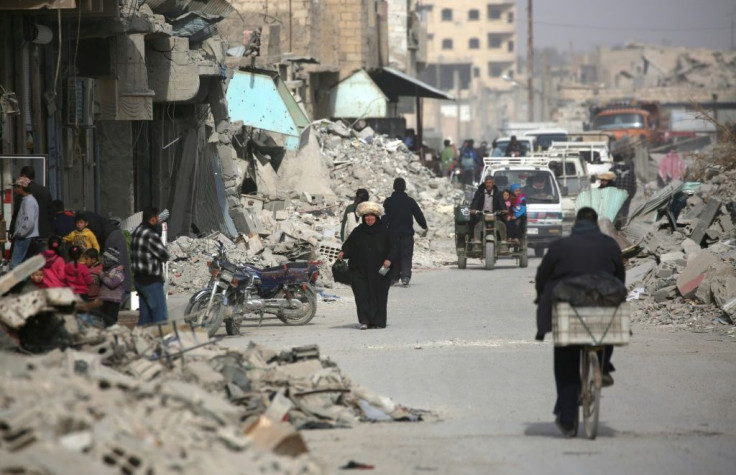 Syrians walk amidst destroyed buildings in Raqa in January 2018 after a huge military ground operation by Kurdish fighters and in the air by US warplanes defeated jihadists from the Islamic State group but left the city completely disfigured
