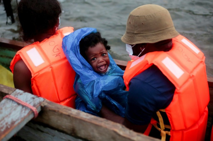 Migrants are given orange life vests and boarded onto canoes that take them along a river to a migrant shelter in Lajas Blancas