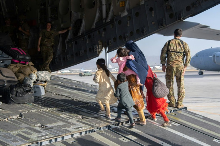 Afghans board a U.S. Air Force C-17 Globemaster III for evacuation at Hamid Karzai International Airport