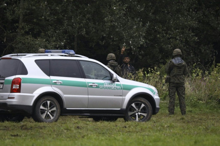 A refugee attempts to communicate with an interpreter, separated by a police cordon, near Bialystok in Poland on the border with Belarus