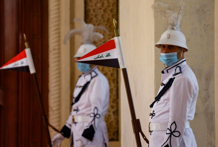 Iraqi honour guard hold national flags ahead of a regional summit in the capital Baghdad