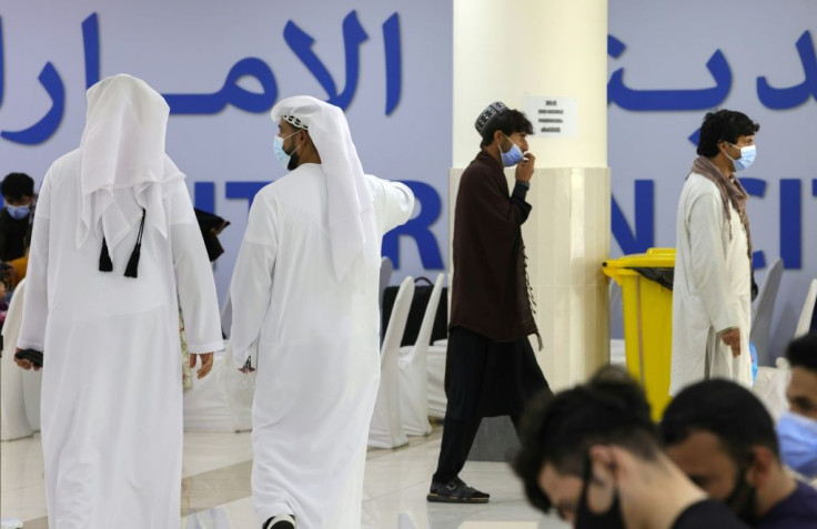 Emirati men walk among refugees who fled Afghanistan after the takeover of their country by the Taliban