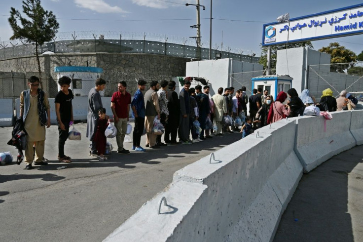 Afghans hoping to leave Taliban-controlled Afghanistan queue at the main entrance gate of Kabul airport