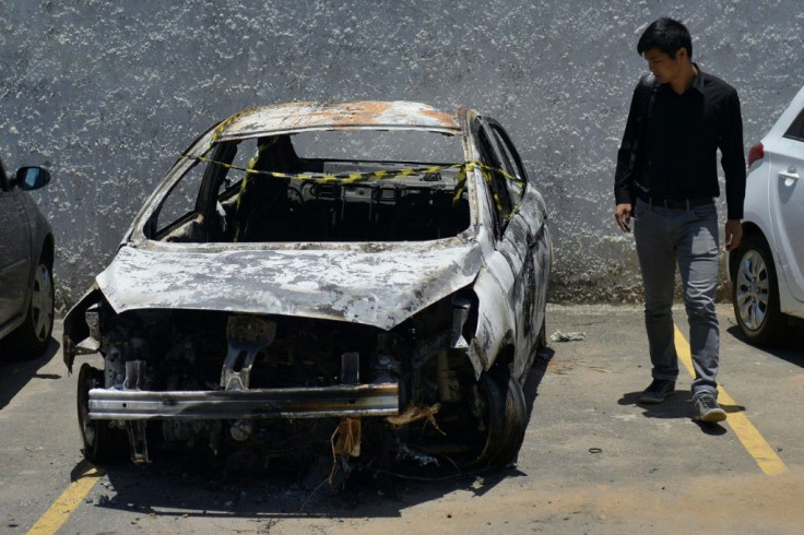 In this photo taken on December 30, 2016 a man looks at the burned-out rental car of Greek ambassador to Brazil Kyriakos Amiridis, at a parking lot outside the police station in Belford Roxo, in the Brazilian state of Rio de Janeiro