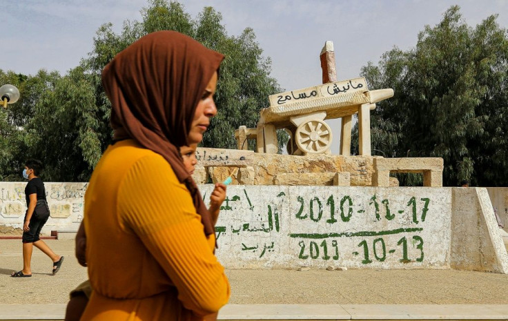 A woman walks past the sculpture of Mohamed Bouazizi's cart in the square named after him in central Sidi Bouzid