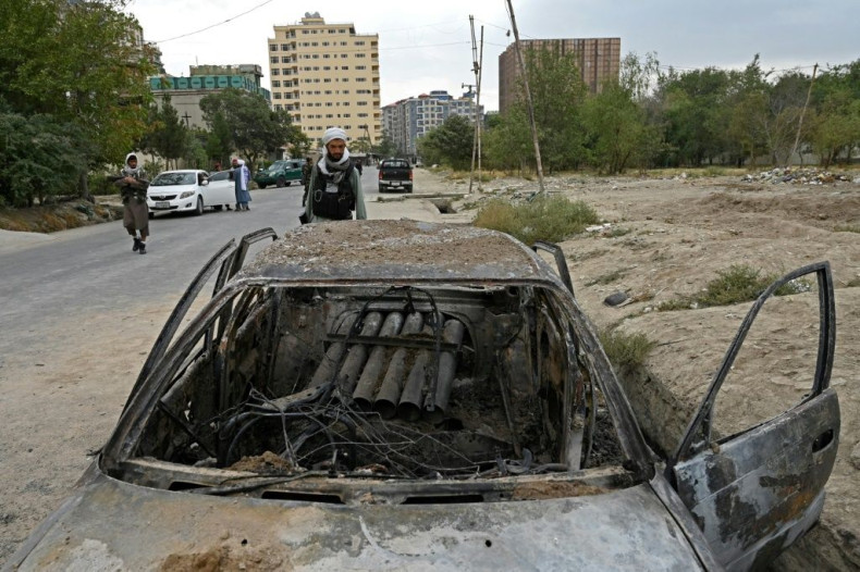 A Taliban fighter investigates a damaged car with what appears to be a damaged launcher in the back, after multiple rockets were fired in Kabul on August 30, 2021