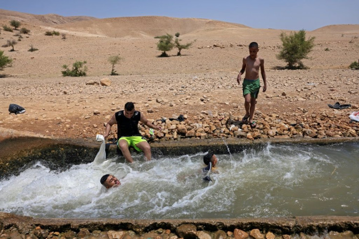 Palestinians cool down in a water canal in the Jordan Valley village of Al-Auja, in the occupied West Bank
