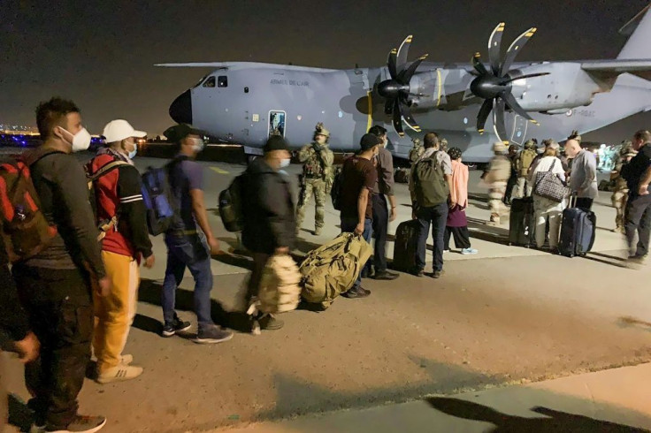 People line up to board a French military transport plane at the Kabul airport on August 17, 2021, for evacuation from Afghanistan after the Taliban's stunning military takeover of the country