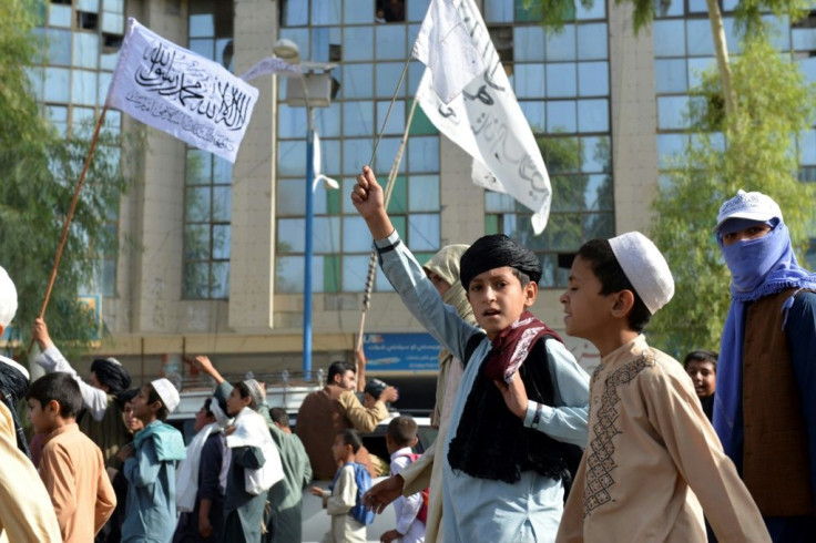 Youths supporting the Taliban wave Taliban flags and shout slogans while marching along a street in Kandahar on Tuesday