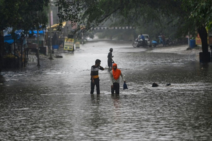 People wade through a waterlogged street in Faridabad, India
