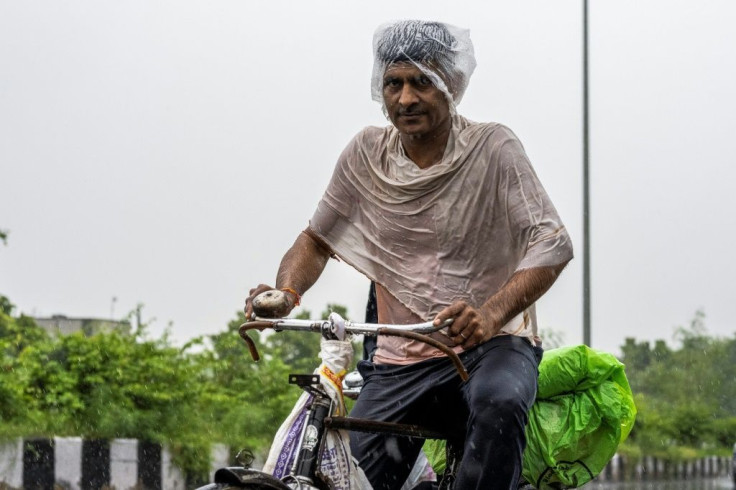 A man rides a bicycle along a street during heavy rain in New Delhi