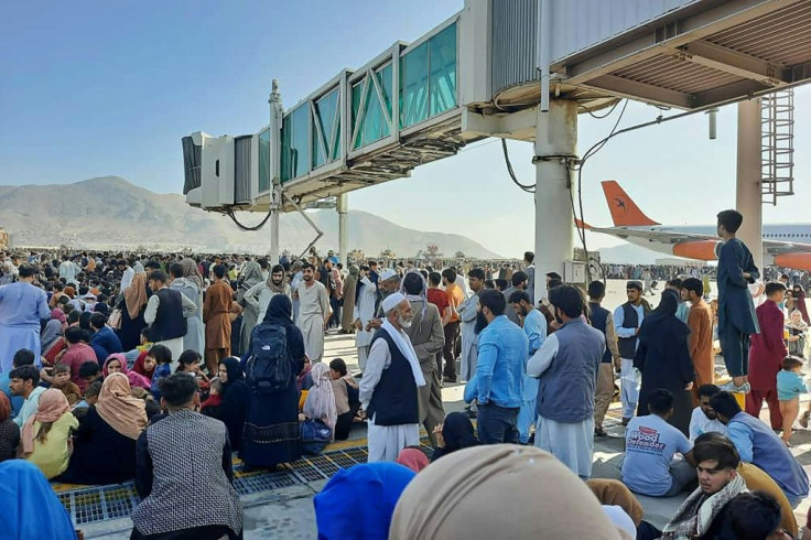 Afghans crowd the tarmac of the Kabul airport on August 16, 2021, to flee the country as the Taliban took control