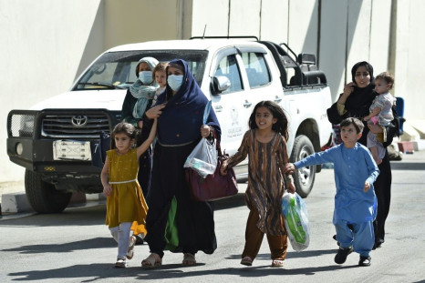 Afghan woman with children, hoping to leave Afghanistan, walk through the main entrance gate of Kabul airport on August 28, 2021 as the US military prepared to leave