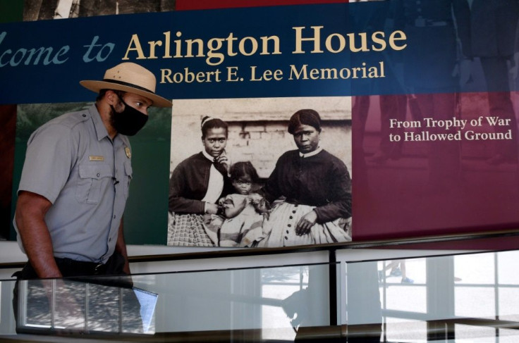 Park Ranger Aaron LaRocca walks past the entrance of Arlington House, featuring a photo believed to be of enslaved housekeeper Selina Gray and two of her daughters