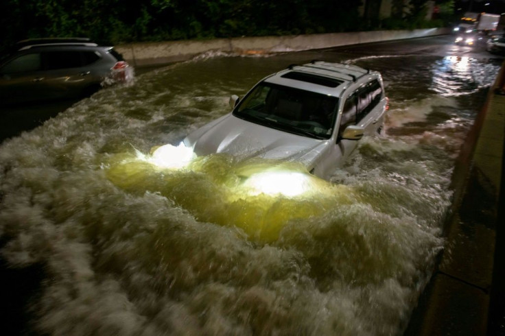 A motorist drives a car through a flooded expressway in Brooklyn, New York early on September 2, 2021, as flash flooding and record-breaking rainfall brought by the remnants of Storm Ida swept through the area
