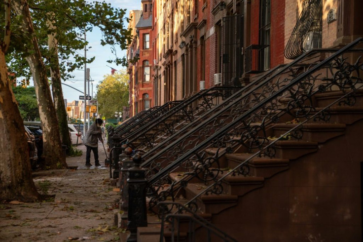 A person sweeps up debris in the front of a brownstone after the extremely heavy rainfall from Hurricane Ida on September 2, 2021, in the Bronx borough of New York City