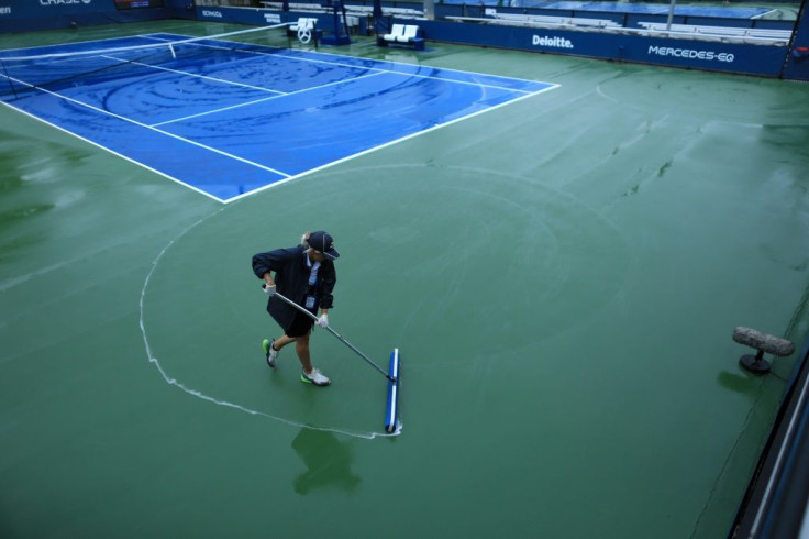 Court staff clean the rain off the courts at the USTA Billie Jean King National Tennis Center in New York, on September 1, 2021